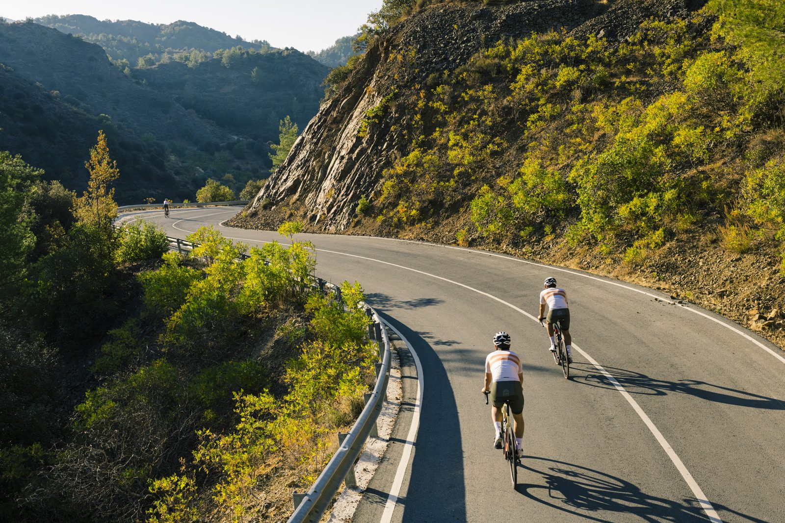 Riders climbing a sunlit mountain road on the route above Lefkara